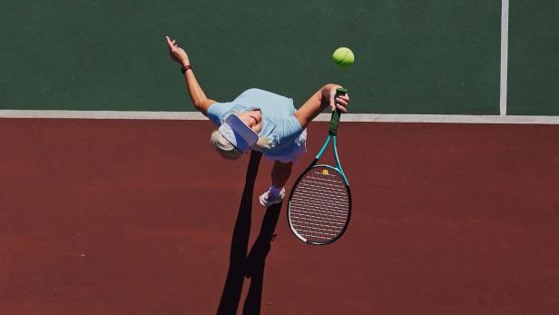 Frau schlägt beim Tennis aus.