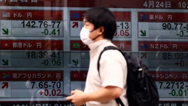 A man walks past an electronic screen displaying exchange rate between Japanese yen and U.S. dollar, and other foreign currencies in Tokyo