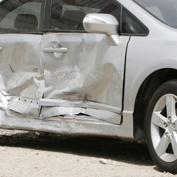Silver car with a large dent in the side, ruining two doors